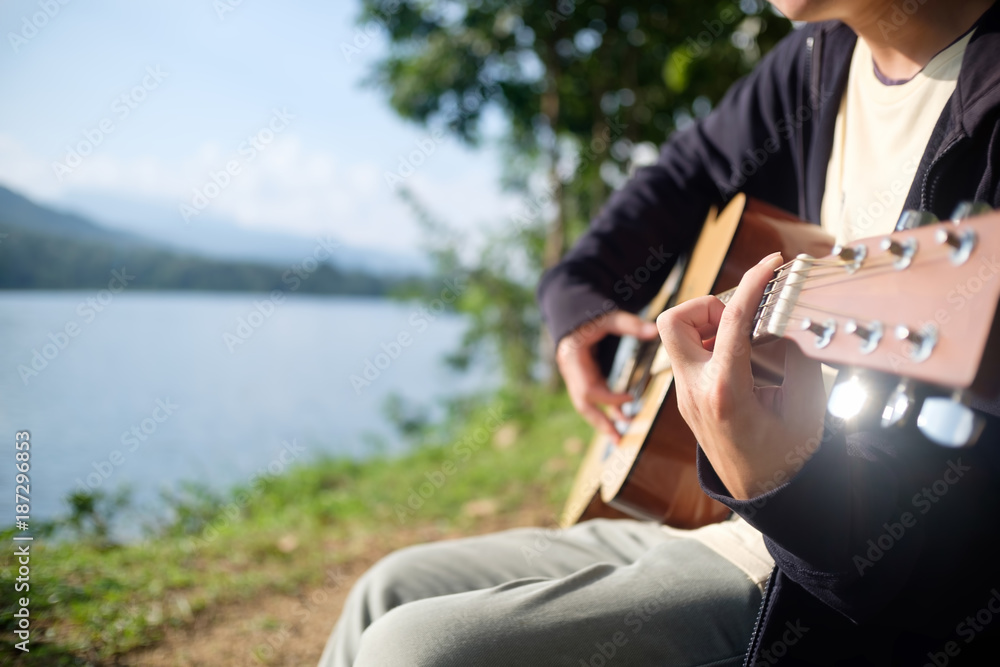 Fototapeta premium Closeup man playing music with guitar in outdoor nature.