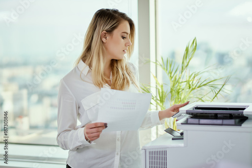 beautiful young businesswoman poses in a sunny skyscraper office