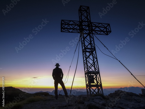 Silhouette of a man on top of a mountain looking into the rising sun
