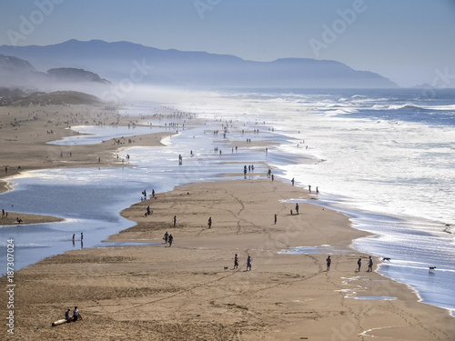Busy beach full of walking and playing people in San Francisco, California