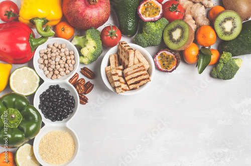 Fruits vegetables frame background. Fresh vegetables, exotic and seasonal fruits, tofu, cereals, pasta, nuts and beans for a vegetarian diet, top view. Copy space, light background.