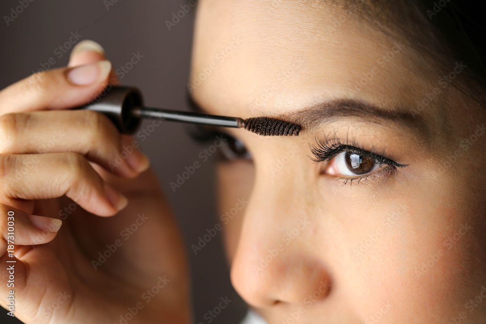 beautiful asia woman Applying makeup - brushing eyebrows.