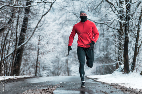 Winter running exercise, runner on road in snowy forest