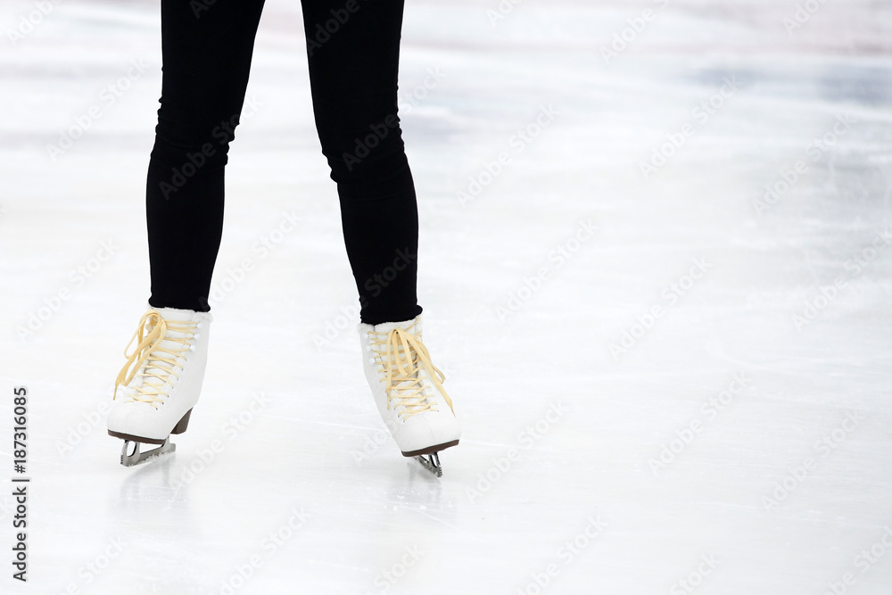 Young woman ice skating outdoors on a ice rink on a freezing winter day - detail of the legs