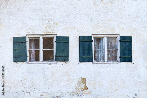 Old rustic windows with wooden shutters on white house