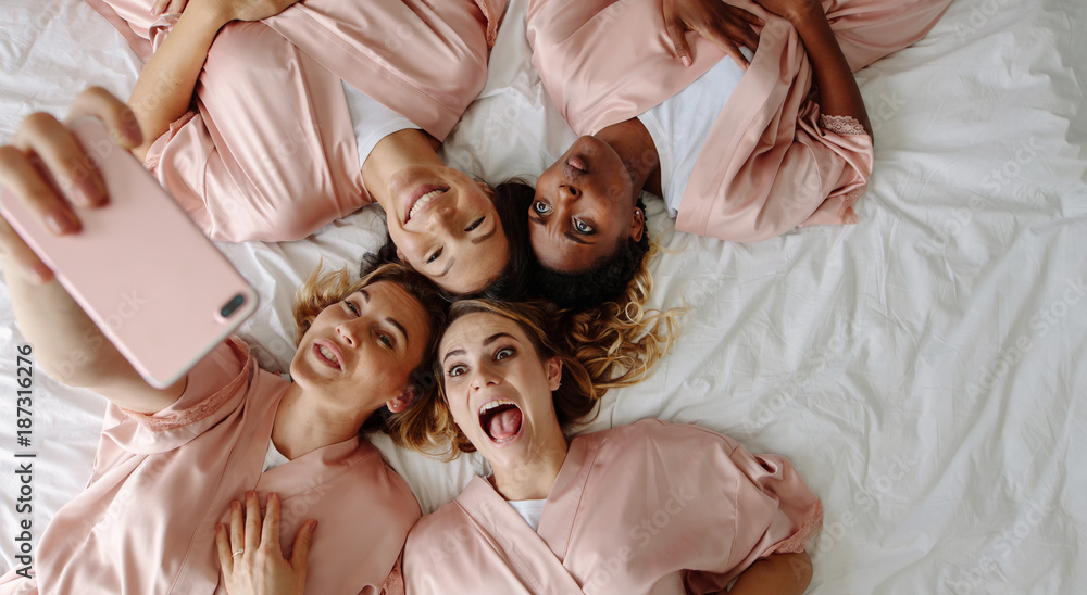 Bride taking selfie with bridesmaids making funny faces