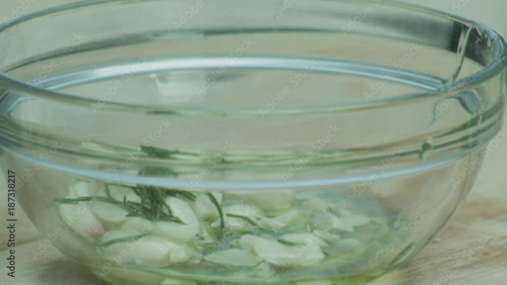 Chef puts garlic, rosemary and parsley in glass bowl Chef puts garlic, rosemary and parsley in glass bowl