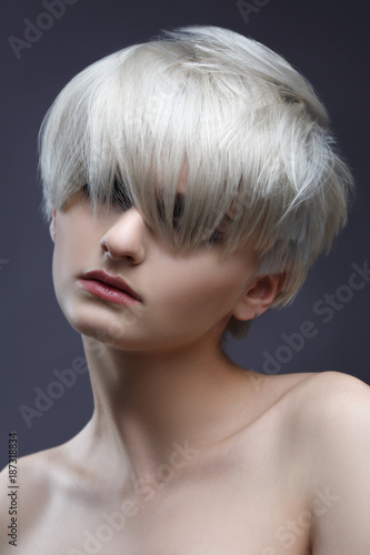 Fashion beauty portrait of a blonde girl with a stylish short haircut, bangs closes her eyes.