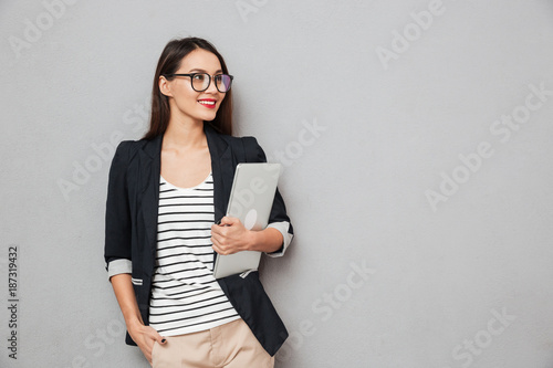 Smiling asian business woman in eyeglasses holding laptop computer