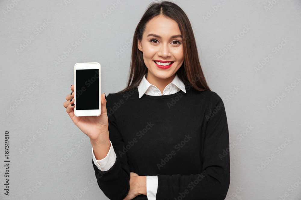 Smiling asian woman in business clothes showing blank smartphone screen Smiling asian woman in business clothes showing blank smartphone screen