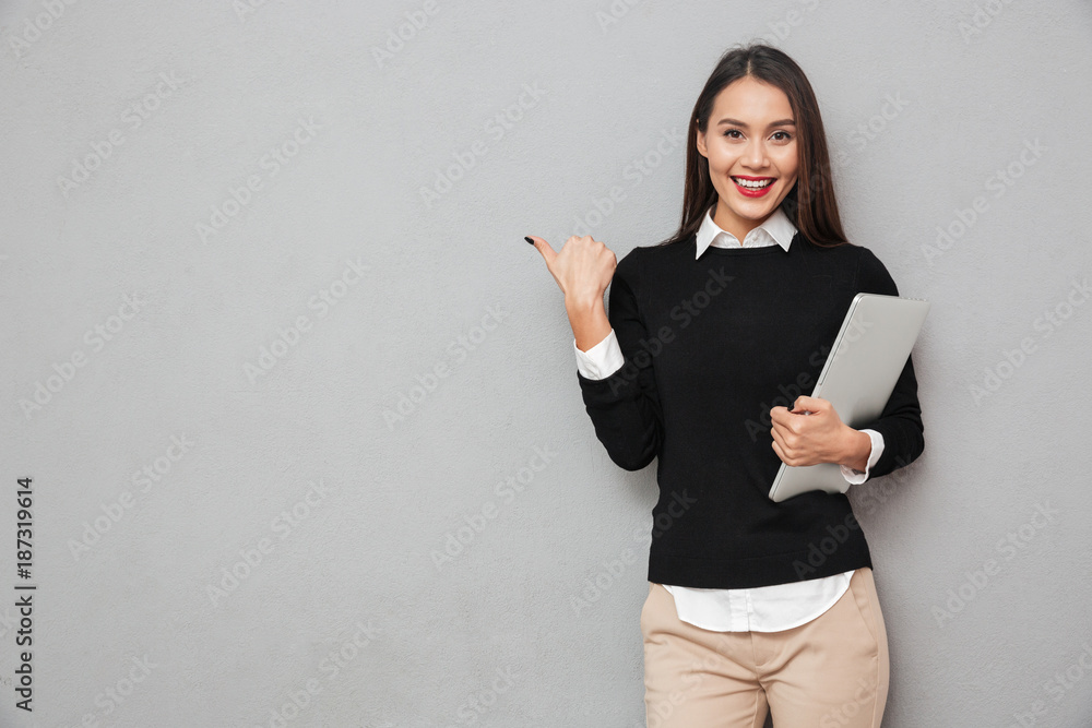 Smiling asian woman in business clothes holding laptop computer Smiling asian woman in business clothes holding laptop computer