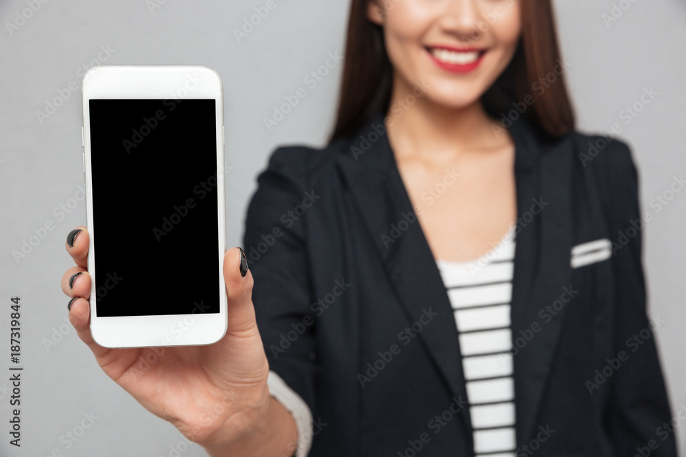 Cropped image of smiling business woman showing blank smartphone screen