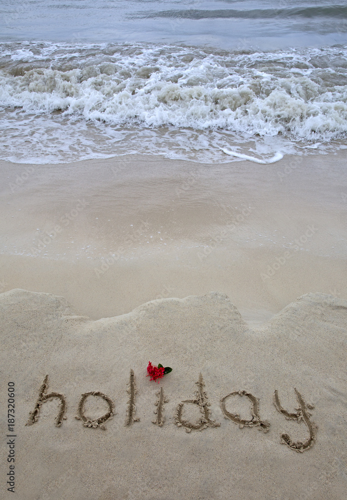 Fototapeta premium The word holiday written on the beach 