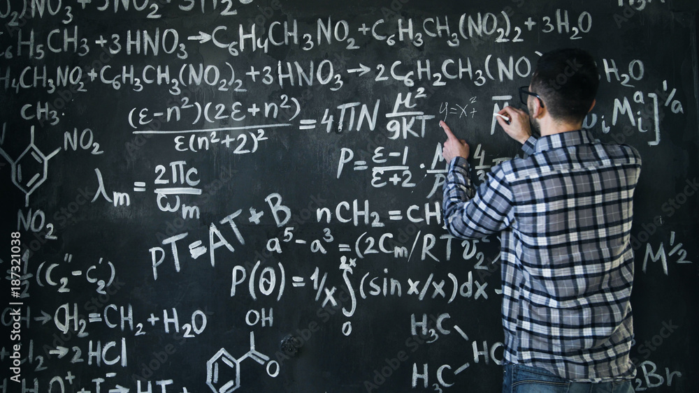 Young scientist man write chock in chemical and mathematical equations wall room interior Young scientist man write chock in chemical and mathematical equations wall room interior