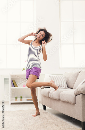 Happy young woman in headphones on beige couch