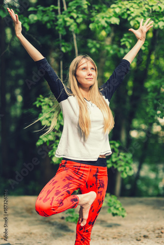 Beautiful young woman doing yoga in the park