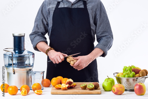 Anonymous man preparing fresh fruit juice using electric juicer, healthy lifestyle detox concept on white background. New year's resolution, fresh start, losing weight concept.