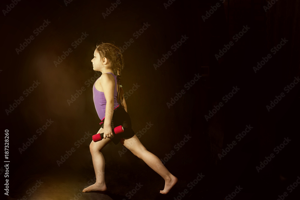 Little caucasian girl with dumbbells