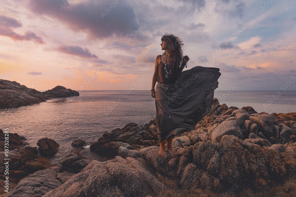 Obraz premium beautiful woman on the top of the rock at sunset over sea background