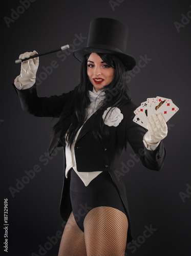 Female magician in performer suit with magic wand and playing cards