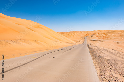 Asphalt road between desert sand.