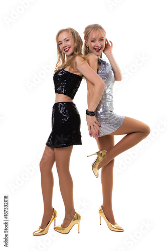 two cute european twin girls dancing in the studio on a white background in shiny dresses - isolated