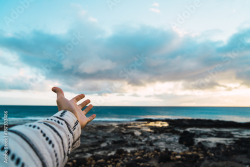 Crop person outstretching hand towards ocean photo