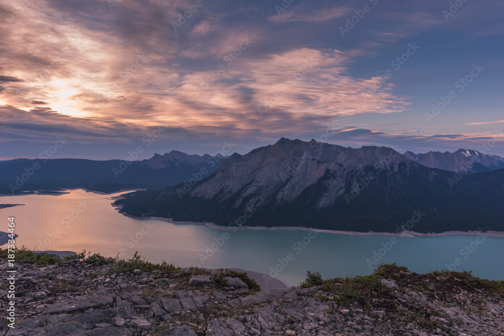 Sunrise at Abraham Lake. Camping on a ridge shows the pastel colored sky early in the morning. Calm and warm scene. There are clouds covering most of the sky.