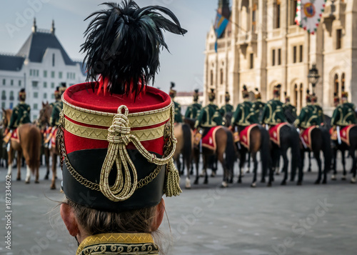 Hussar traditional military hat closeup. Background with line up of hussar cavalry on horses in front of the Parliament House during the 15 March military parade in Budapest  Hungary. 