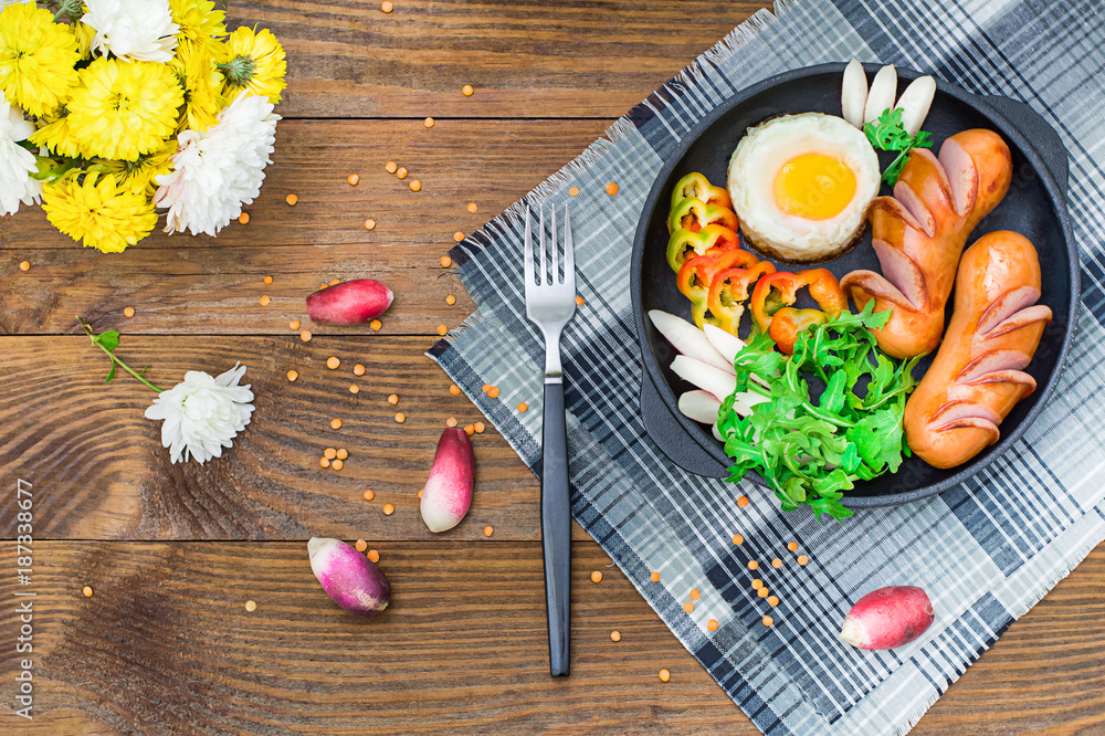 Fried eggs with sausages, rucola, bell pepper and radish. Wooden rustic background. Selective focus. Top view Fried eggs with sausages, rucola, bell pepper and radish. Wooden rustic background. Selective focus. Top view