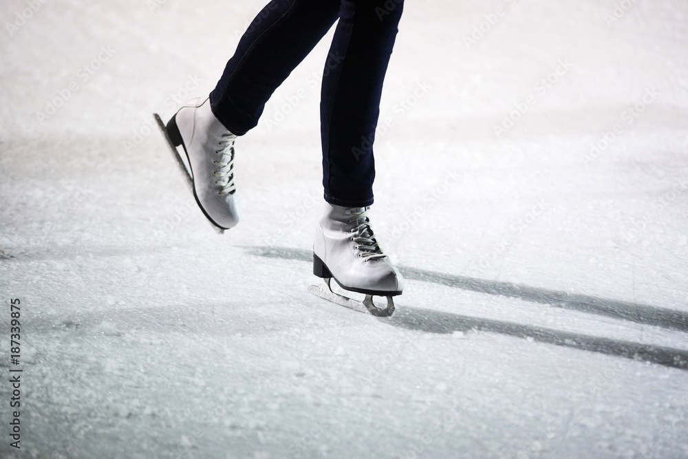 Young woman ice skating outdoors on a ice rink on a freezing winter day - detail of the legs Young woman ice skating outdoors on a ice rink on a freezing winter day - detail of the legs