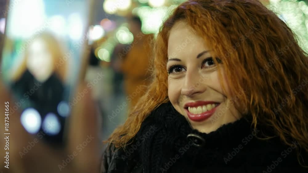 Beautiful curly red hair woman makes selfie by mobile at city holiday close-up Beautiful curly red hair woman makes selfie by mobile at city holiday close-up