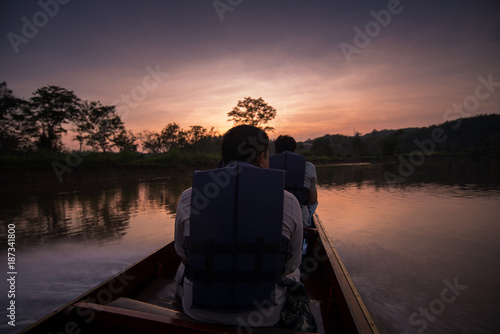 Man in a boat on a river at sunset.