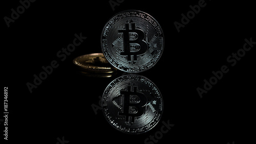 Two bitcoins reflecting on dark glass table © Thunderstock