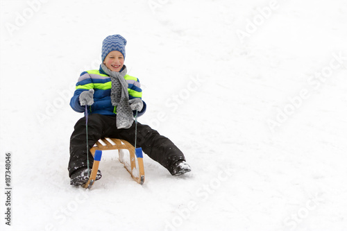 Kid sliding with sledge in the snow.