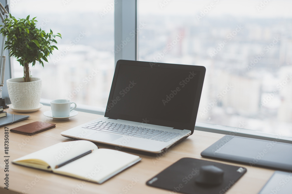 Sideview of office desktop with blank laptop and various tools. Sideview of office desktop with blank laptop and various tools.