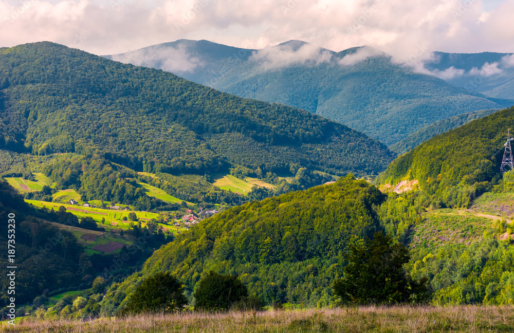 Obraz premium village in the valley of Carpathian mountains. lovely countryside scenery in early autumn with clouds rising from the forest on the distant ridge
