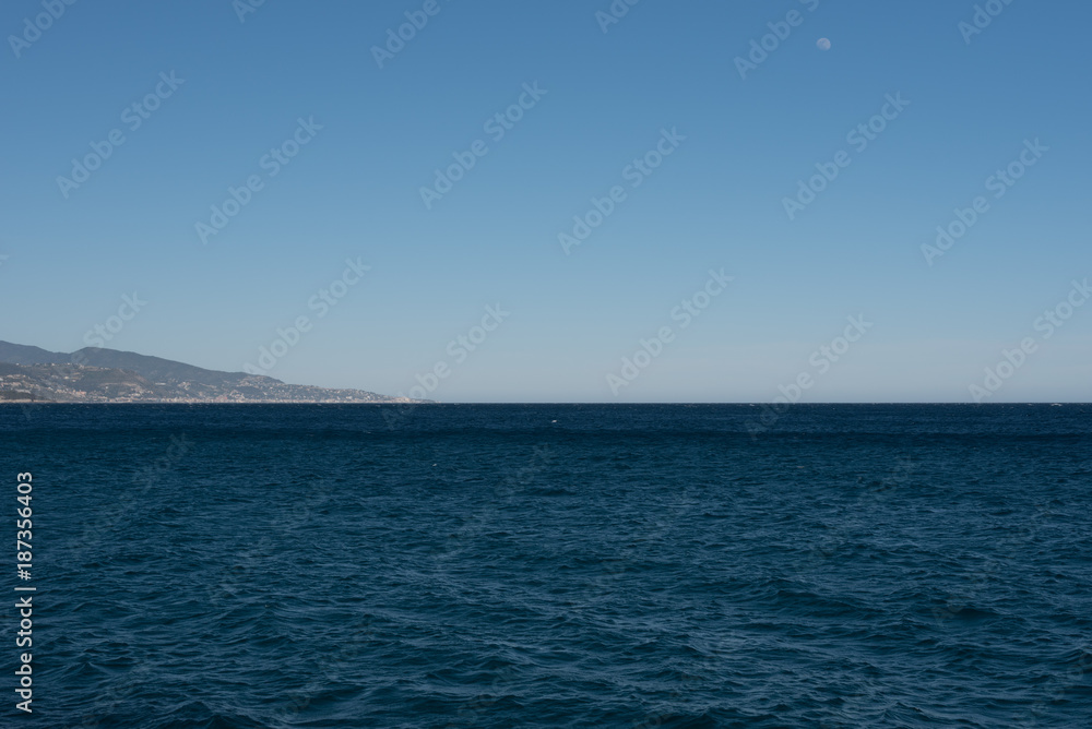 Ocean sharp blue sky and seagulls with the moon