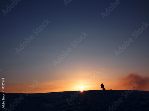 Silhouette of a man standing on snow mountain toward sunset 