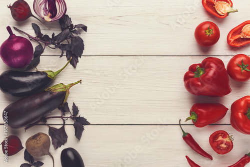 Border of various red and violet vegetables on white wood