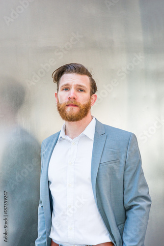 Portrait of Young American Hipster Businessman with full beard on silver metal background.. photo