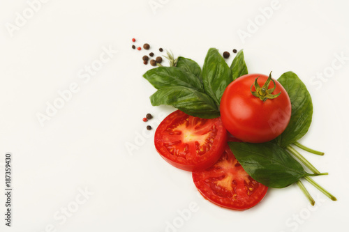 Red tomatoes and basil leaves isolated on white