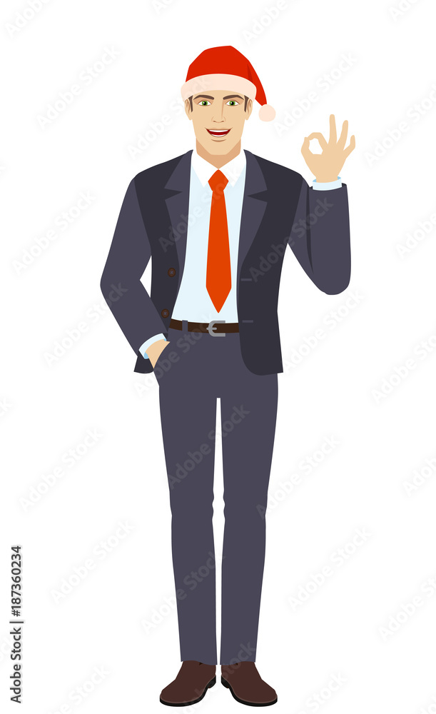 Businessman in Santa hat with hand in pocket showing a okay hand sign Businessman in Santa hat with hand in pocket showing a okay hand sign