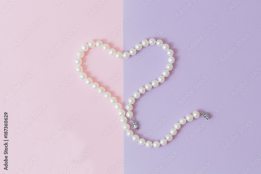 Pearl heart on a pink-gray background. Flat lay, top view