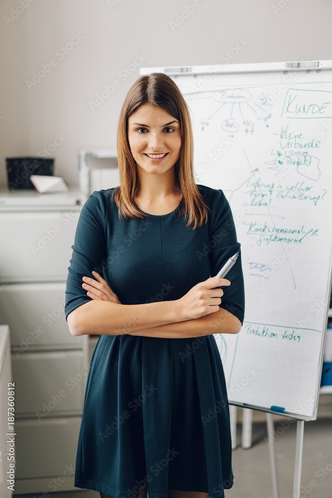 Young smiling woman standing against flip chart Young smiling woman standing against flip chart