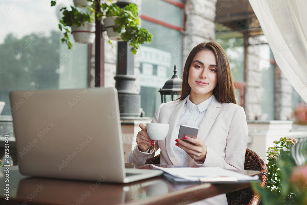 Young businesswoman outdoors using smartphone and drinking coffee Young businesswoman outdoors using smartphone and drinking coffee