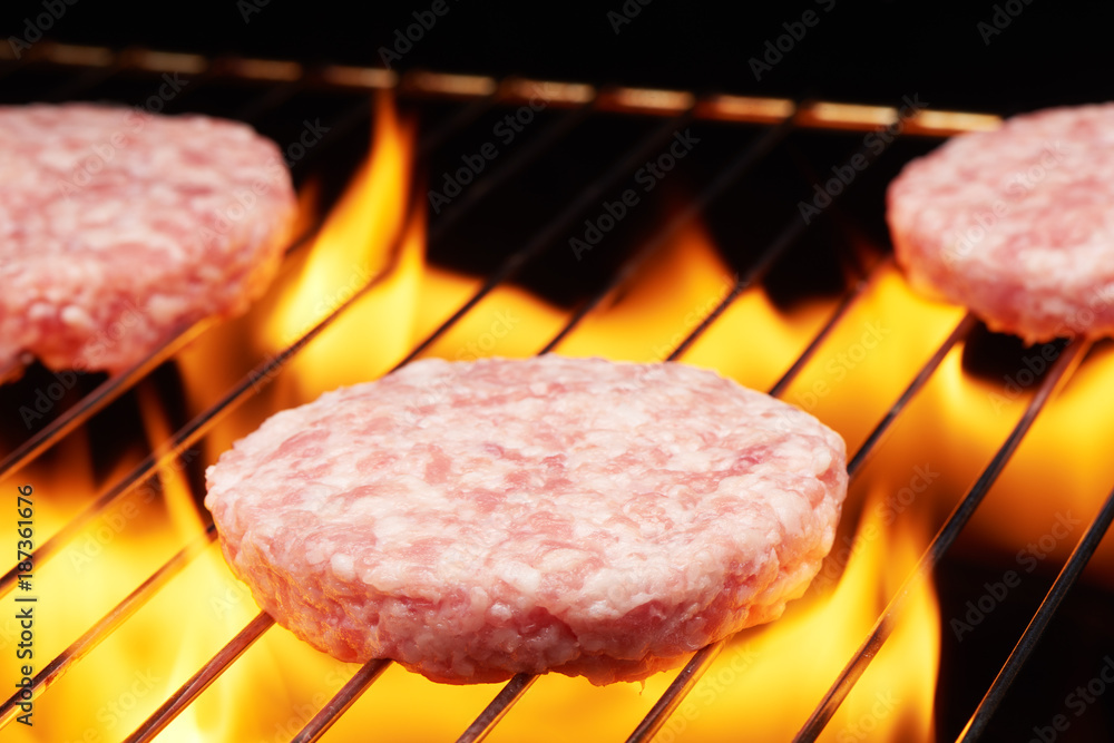 Raw hamburgers on grill with flame Raw hamburgers on grill with flame