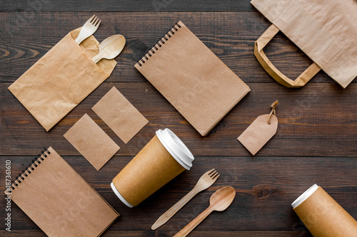 Set of recycle brown paper bag, disposable tableware cup, spoon, fork, notebook on wooden background top view pattern