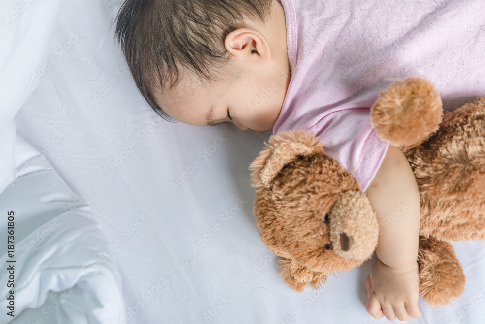Asian baby sleeping on the bed,thailand people,relax time,bear doll Asian baby sleeping on the bed,thailand people,relax time,bear doll