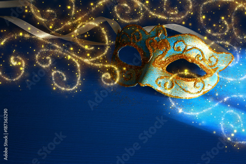 Image of elegant blue and gold venetian, mardi gras mask over blue background.